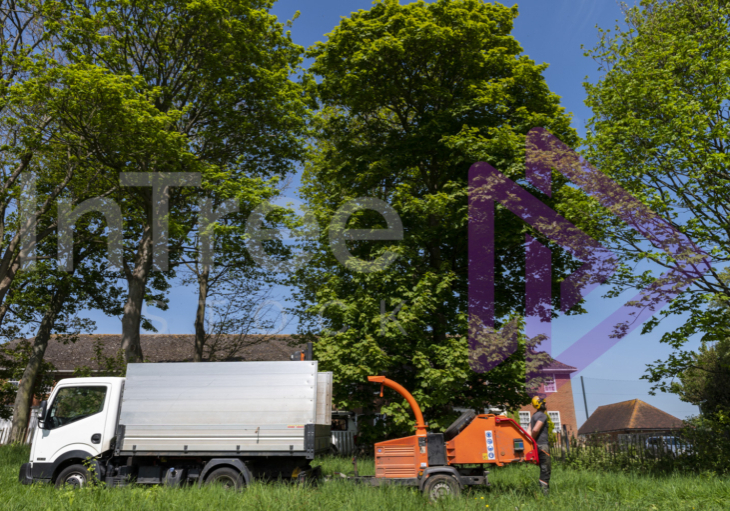 Chip truck and chipper in field adjacent to residential homes in UK