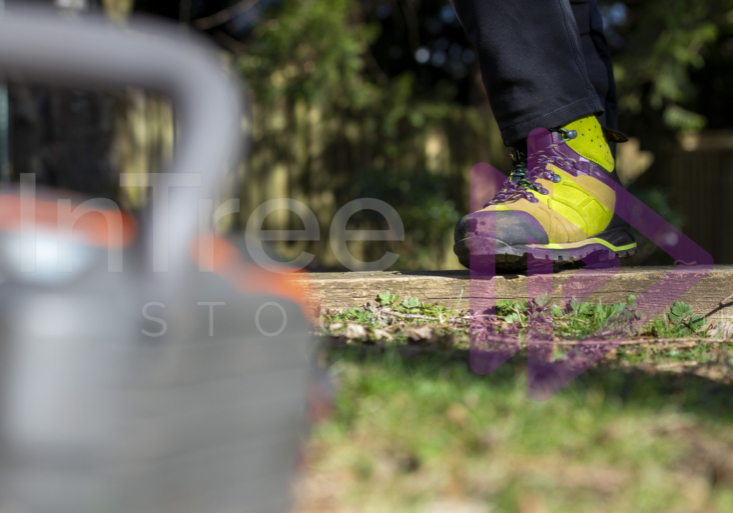 Green chainsaw protective boots in sunlight