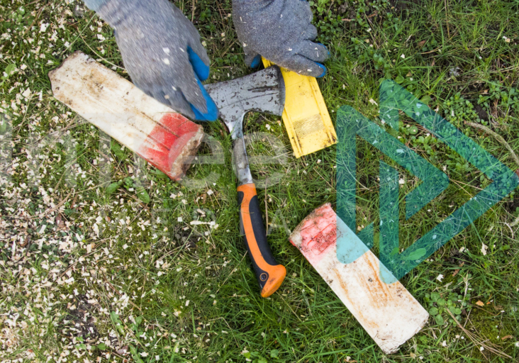 Hands reach for felling wedges and hatchet on the ground