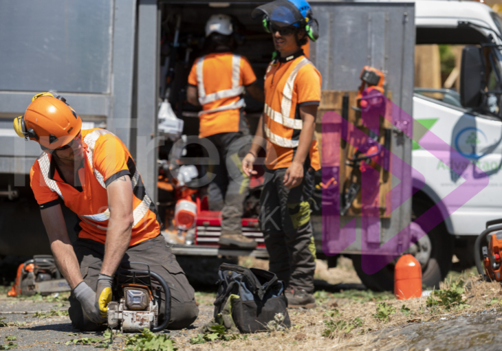 Male arborist tightening chainsaw chain