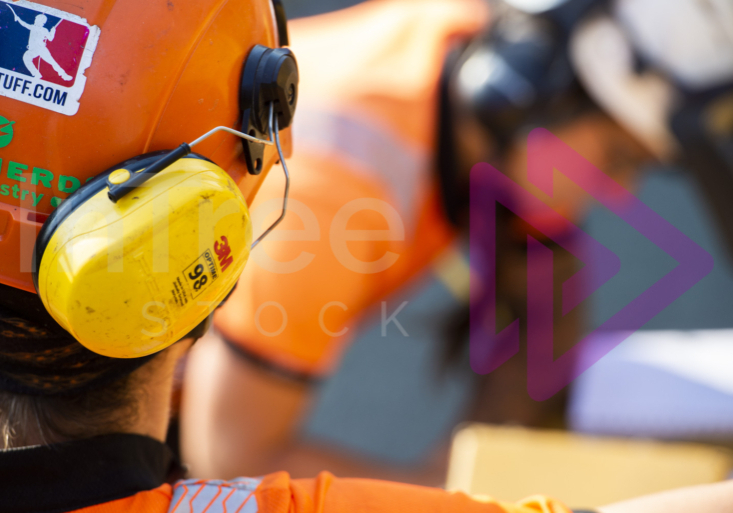 Yellow 3M Ear defender on helmet with woman blurred in background